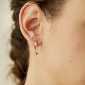 Elegant gold sunburst hoop earring with sparkling cubic zirconia on a model ear