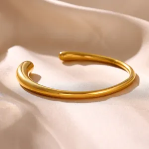Detailed macro view of a minimalist 18k gold plated stainless steel irregular open cuff bracelet
