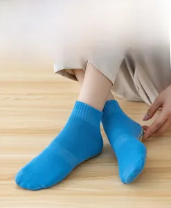 Close-up of bright blue non-slip yoga socks with yellow grip dots on wooden floor.