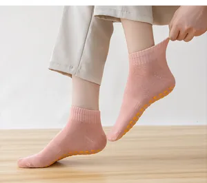 Close-up of pink anti-slip yoga socks with yellow silicone grippers on wooden floor