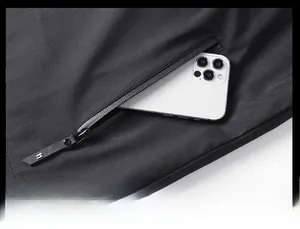 Detailed view of a functional side zipper pocket on a black hooded jacket with a phone