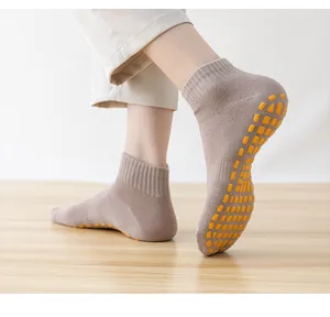 Detailed view of taupe anti-slip yoga socks featuring bright yellow rubber grippers