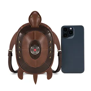 Comparison of a small punk style turtle-shaped crossbody bag with a smartphone for scale
