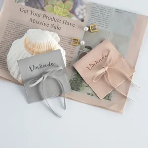 Square microfiber faux leather jewelry pouches in grey and pink with ribbon ties