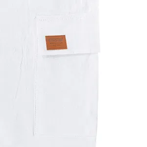 Close-up of white cargo pocket on linen-blend shorts with decorative brown SPORT patch label