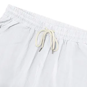 Close-up detail of elastic waistband and drawstring on white linen beach shorts