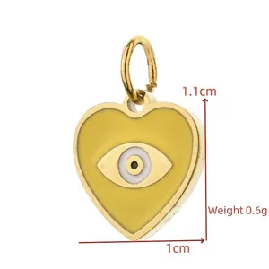 Macro view of a gold-plated heart pendant featuring a yellow evil eye enamel design