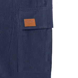 Macro detail view of cargo pocket with brown leather patch on navy blue linen shorts