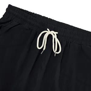 Close-up of men's black linen shorts showing elastic waistband and white drawstring.
