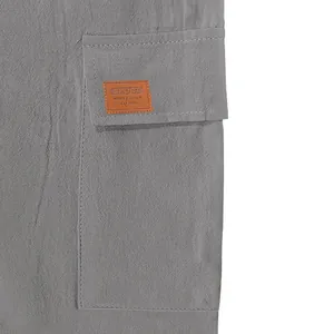 Close-up of decorative sport patch and stitching on a grey linen cargo shorts pocket