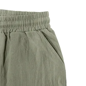Detail view of elastic waistband and side pocket on olive green men's linen shorts.