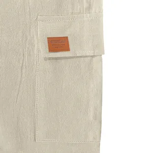 Detail view of linen cargo shorts pocket with brown decorative patch.