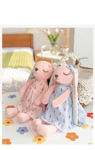Close-up of cute plush long-eared rabbit dolls in pink and blue floral dresses