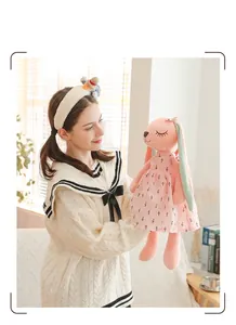 Close-up of a cute pink long-eared rabbit plush doll wearing a small patterned dress