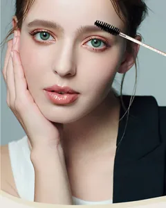 Close-up of a model using a disposable spiral eyebrow brush with a glitter crystal rod
