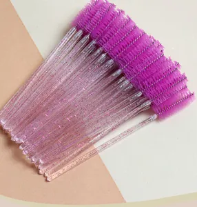Close-up of disposable eyelash brushes with purple spiral heads and glittery handles