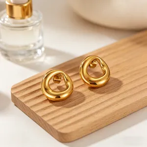 Close-up of gold irregular circular titanium steel stud earrings on a wooden display.
