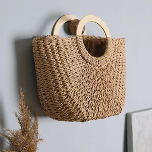 Detailed view of handmade woven straw beach bag featuring round wooden handles