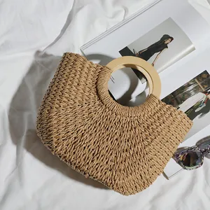 Detailed view of a vintage hand-woven straw beach bag featuring circular wooden handles.