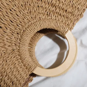 Close-up detail of a retro straw woven beach bag featuring a smooth circular wooden handle