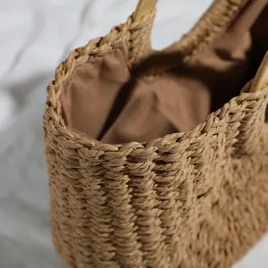 Close-up detail of vintage straw woven handbag showing brown lining and wooden handle