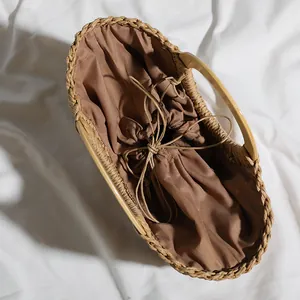 Detailed view of straw bag interior with brown drawstring liner and wooden handle