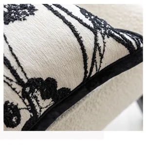 Close-up of black floral embroidery and velvet piping on a beige textured cushion cover