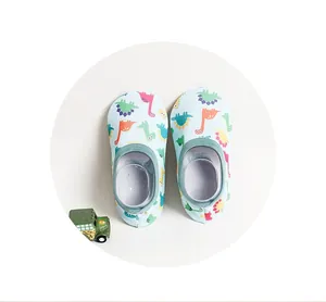 Detailed top-down view of light blue baby floor socks with cartoon dinosaur prints