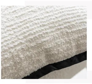 Close-up detail of textured boucle throw pillow cover with black velvet piping.
