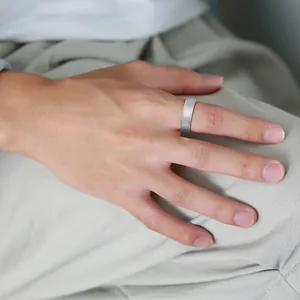 Detailed view of a minimalist silver tungsten steel ring worn on a male finger in daily life