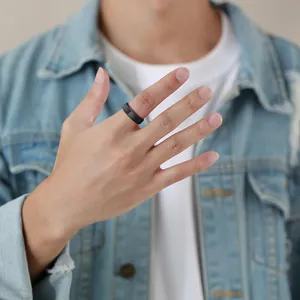 Minimalist men's black tungsten steel ring shown worn on finger with denim jacket