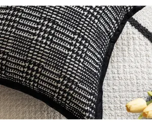 Close-up of black and white textured bouclé pillow cover with elegant black piping