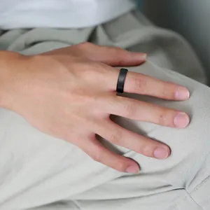 Close-up view of a minimalist black tungsten steel ring worn on a man's finger for style