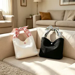 Detailed view of two pleated tote bags featuring floral ribbon handles in black and white colors.