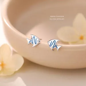 Close-up of S999 sterling silver fish stud earrings with blue enamel waves.