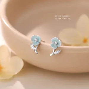 Detailed macro view of light blue flower stud earrings featuring elegant zircon stones