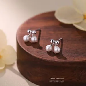 Close-up view of elegant S999 silver bow earrings with delicate pearl drop design