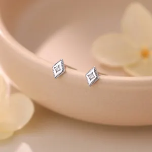 Close-up view of elegant S999 sterling silver rhombus stud earrings with white zircons.