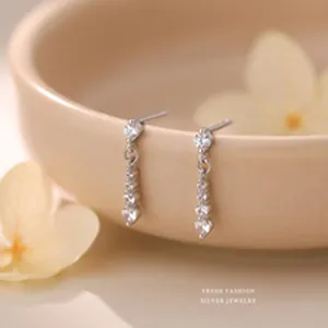 Close-up of silver drop earrings with cubic zirconia studs in a minimalist design.