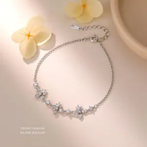 Close-up of a sparkling sterling silver bracelet with zircon butterfly charms on warm background