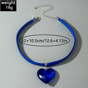 Detailed view of a blue velvet choker necklace with a blue glass heart pendant charm.