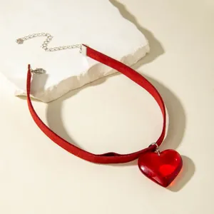 Detailed view of a red velvet choker featuring a translucent red heart pendant