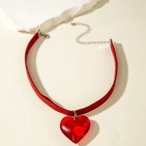 Detailed view of a red velvet gothic choker with a glass heart-shaped pendant.