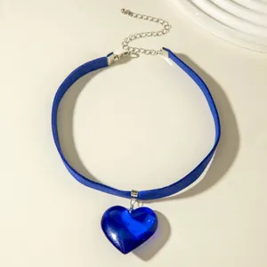 Close-up of a blue velvet choker necklace featuring a large blue glass heart pendant