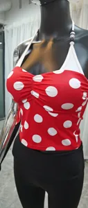 Détail d'un haut de yoga licou à pois rouges avec perles décoratives sur la bride