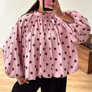 Detail of pink polka dot blouse with high neck and voluminous lantern sleeves.