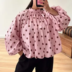 Close-up detail of the elegant pink polka dot blouse featuring loose long sleeves