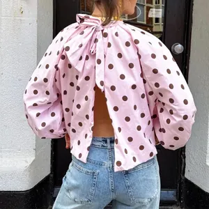 Detailed back view of pink polka dot puff sleeve blouse with bow tie and open back