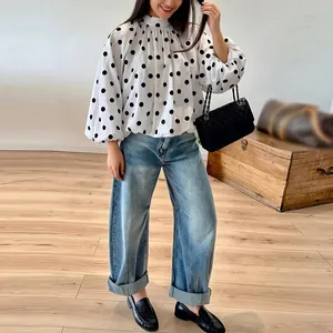 Detail of white loose-fit blouse with large black polka dots and puff sleeves