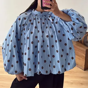Detailed view of voluminous puff sleeves on a blue polka dot blouse